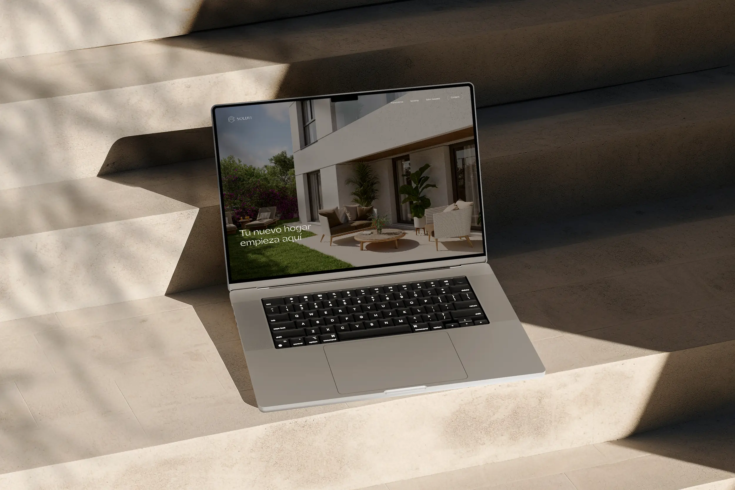 Open laptop on beige stone stairs displaying a real estate homepage with a modern outdoor seating area and greenery on screen.